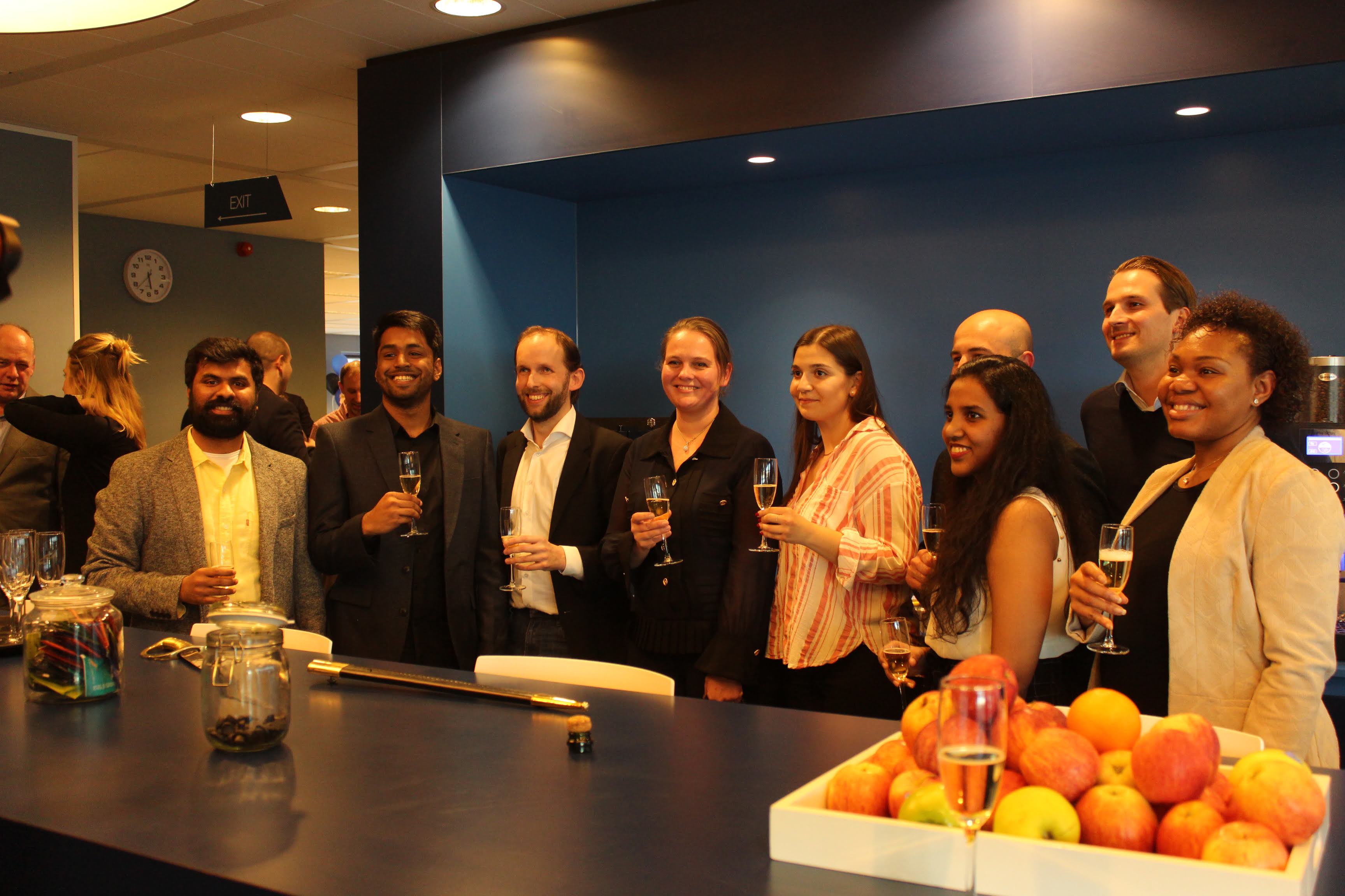 The entire Envision team and 4impact team pose together for a picture, each holding a champagne glass and smiling