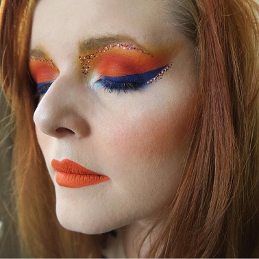 A photo of Lucy Edwards, with orange and blue glittery make-up.