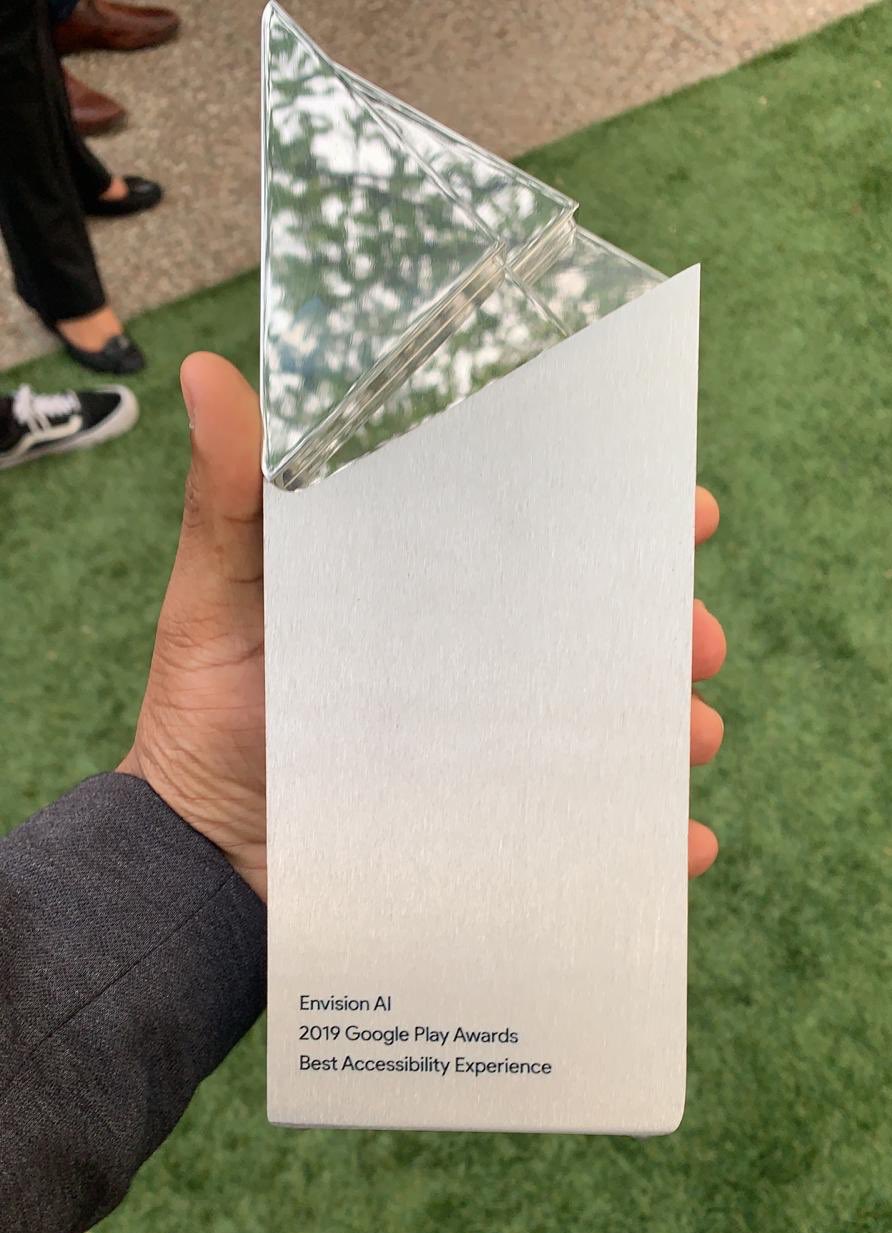 Karthik Kannan holding the Google Play Award in his hand with Envision AI etched on it.