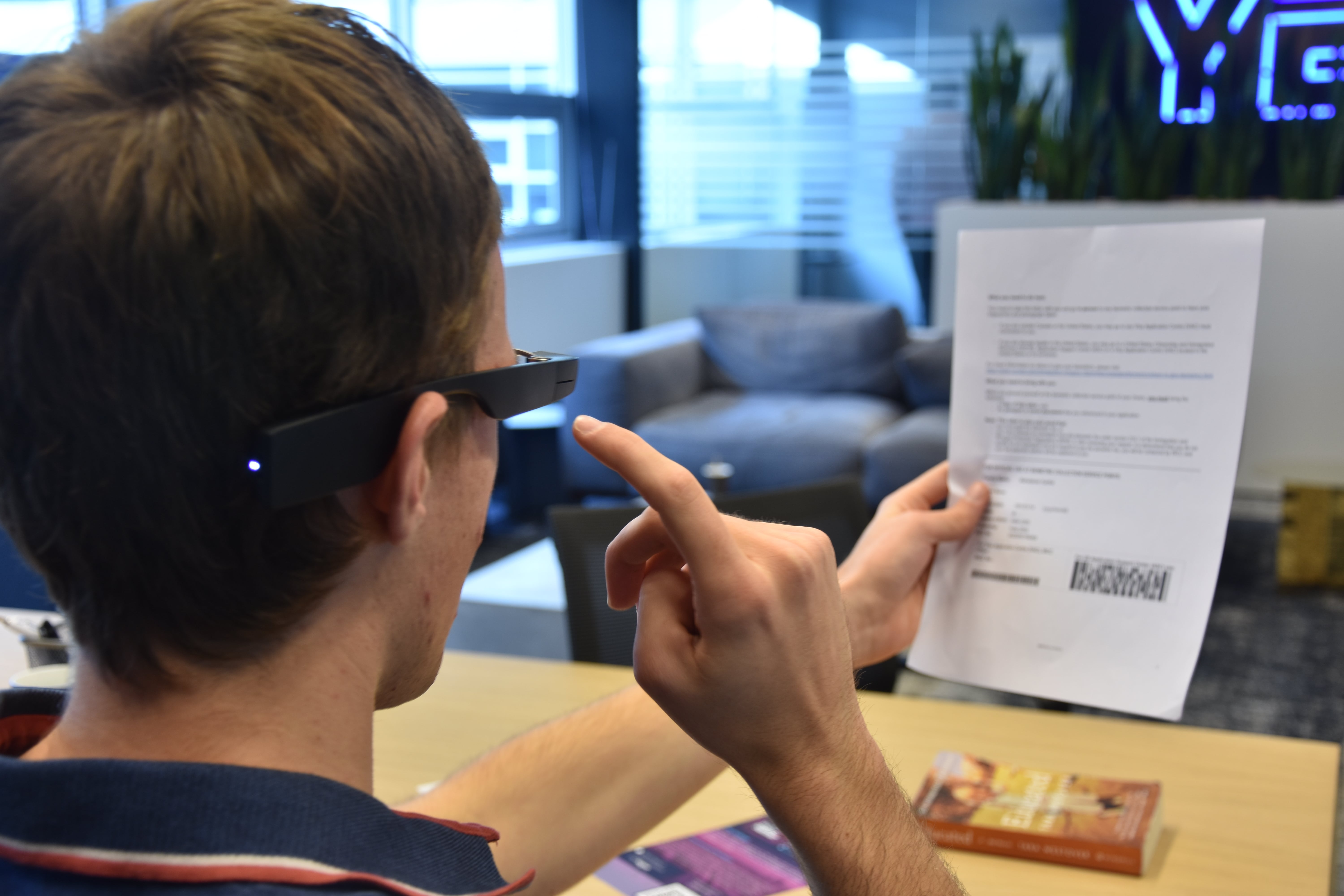 Jesse taking a picture of a document to read it with the Envision Glasses