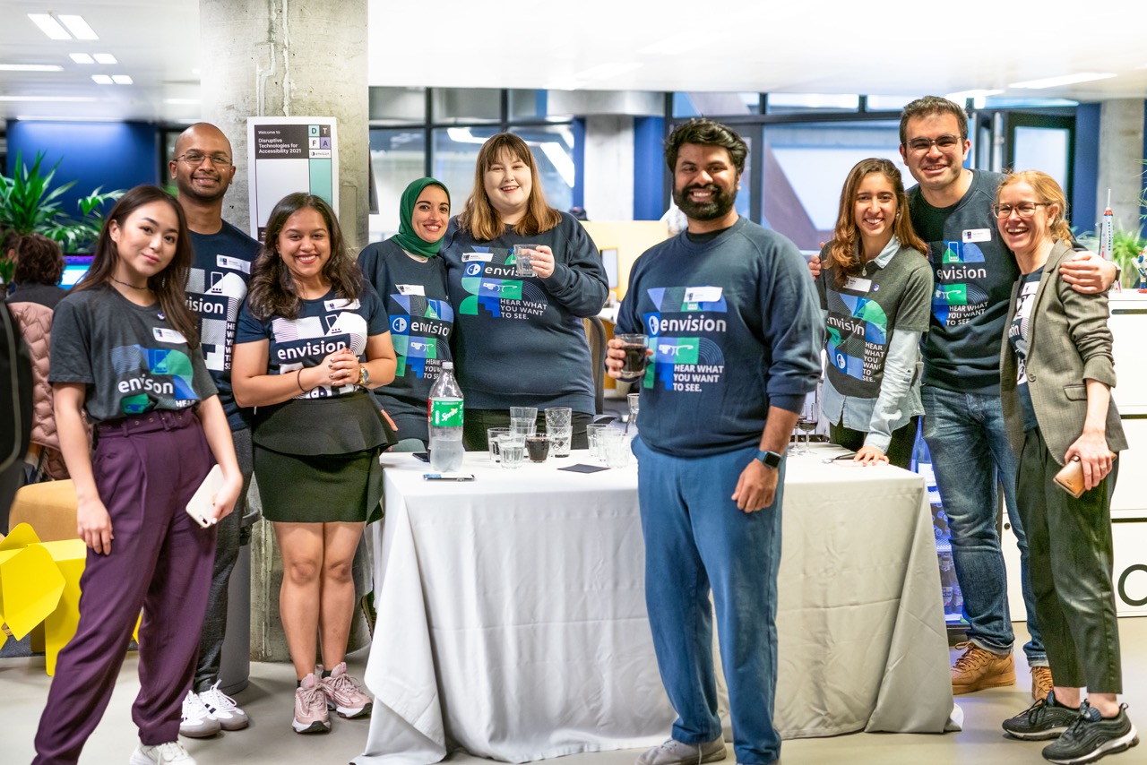 Envision team with drinks in their hand and big smiles on their face posing for a quick picture