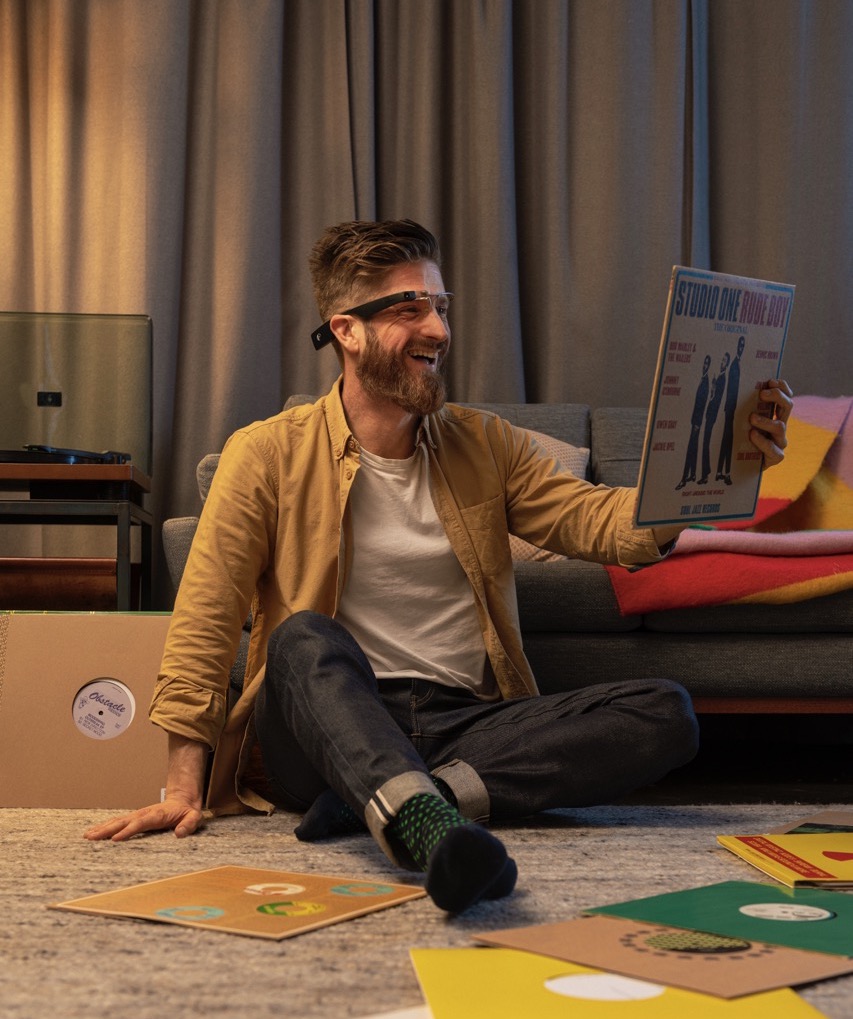 A person sitting with vinyl and reading the cover with Envision Glasses