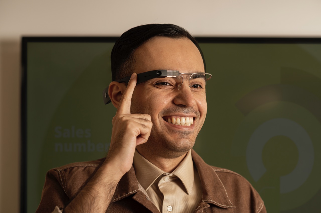 A person wearing the Envision Glasses and tapping the touchpad with his right finger.