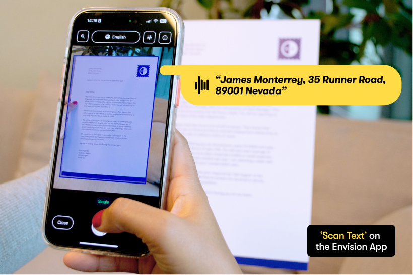Photo of a person holding a phone to scan a document with the Envision App. It shows a yellow speech bubble which means the content of the document is spoken out. Bottom-right text box states: Scan Text on the Envision App. Scan Text boasts of an impressive OCR, with the ability to understand over 60 languages.