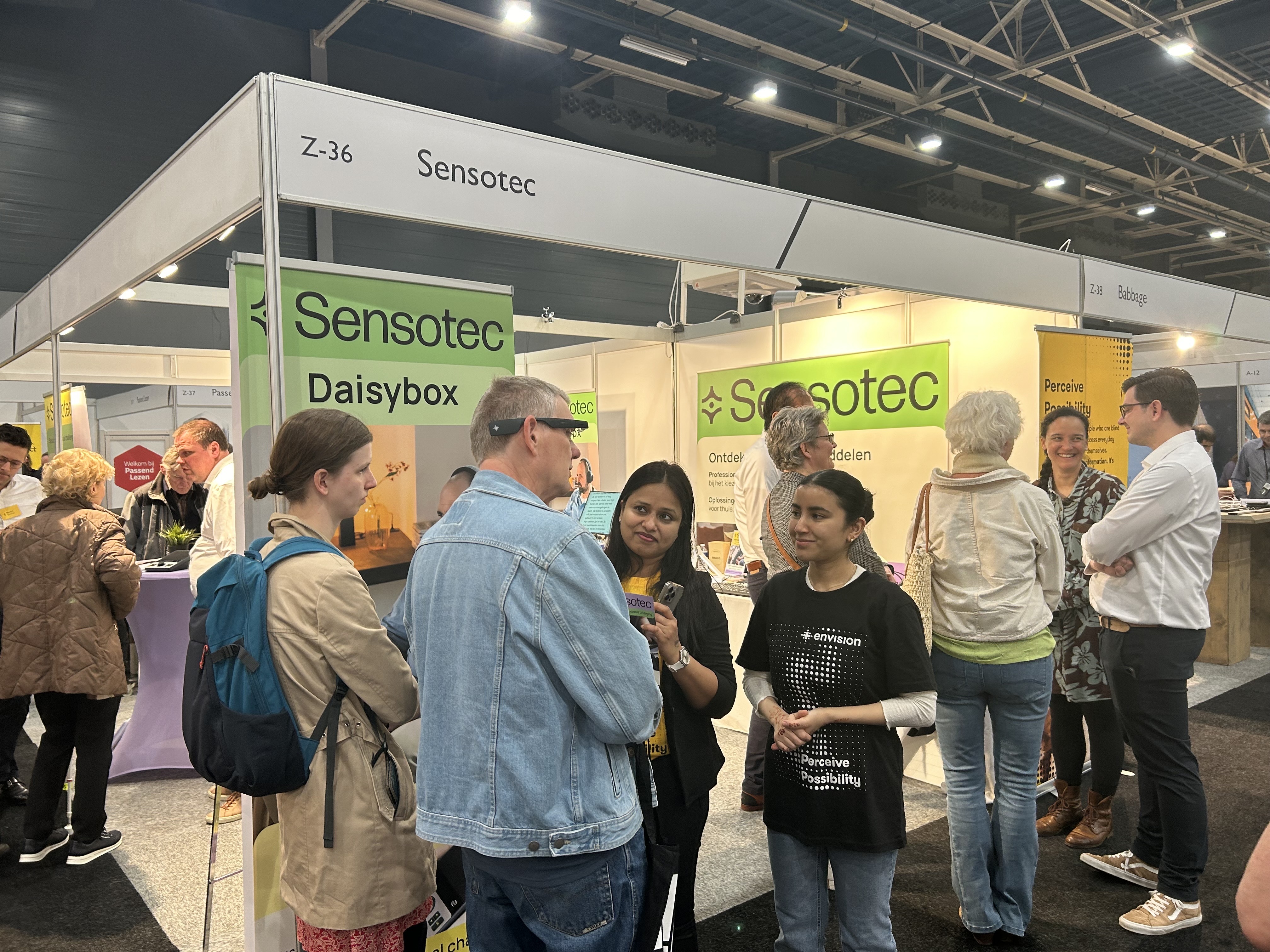 Visitors interact at the Sensotec booth during ZeiZo, featuring informative displays and engaged conversations.