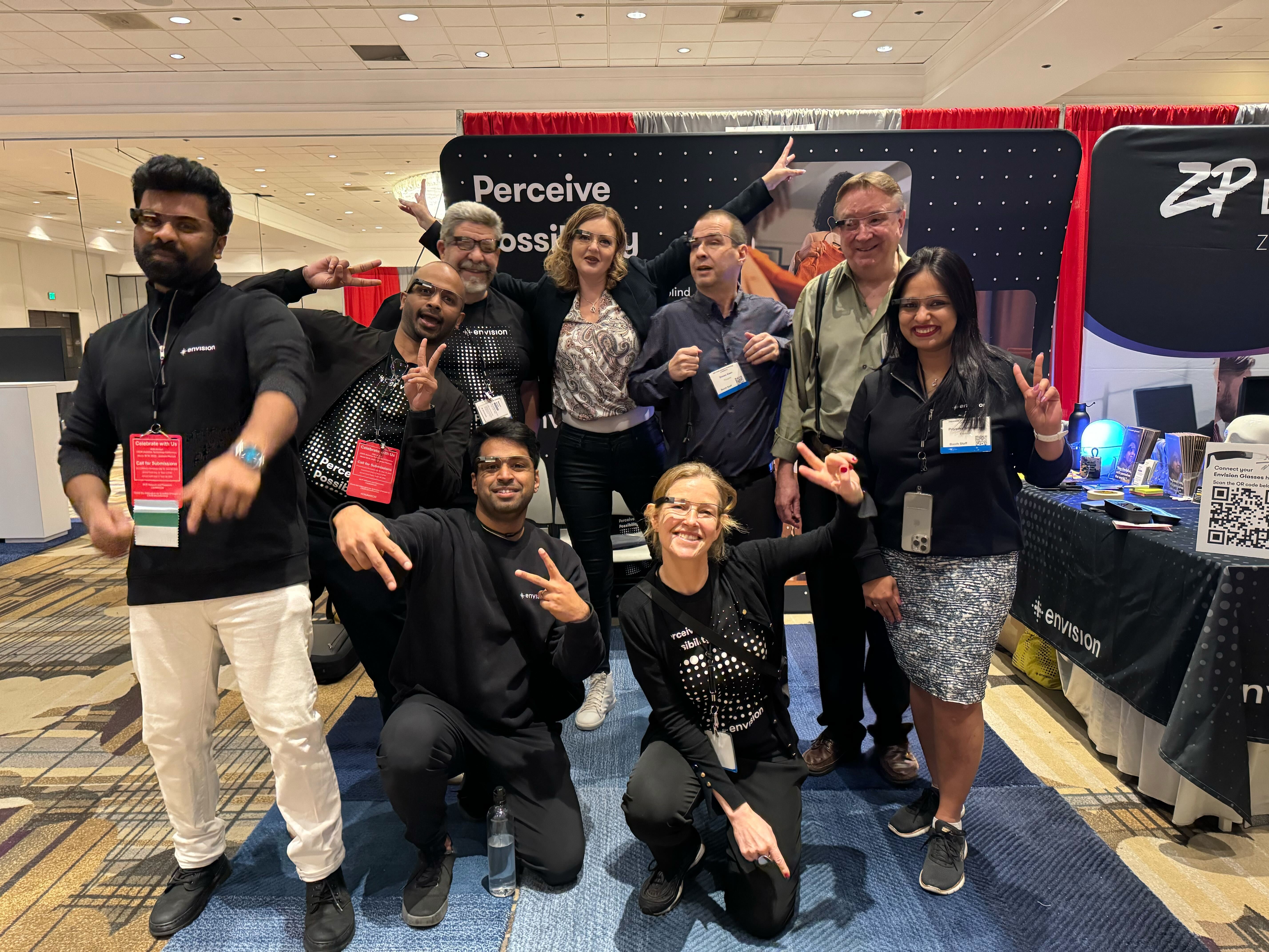 The Envision team posing at a conference booth at CSUN (California) with playful gestures and smiles.