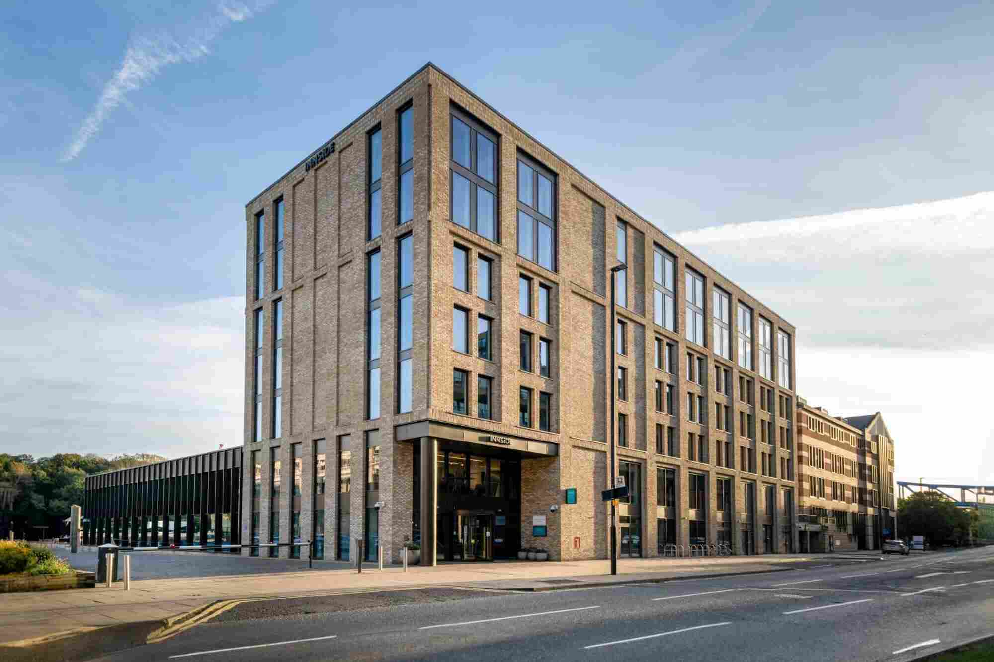 A large building that consists of 5 floors. In front of the building is a two-way street.