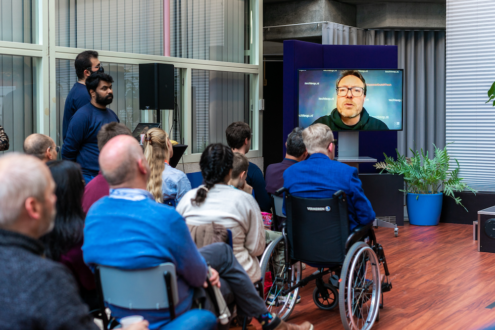 People looking at a presentation of Constantijn van Oranje-Nassau on tv