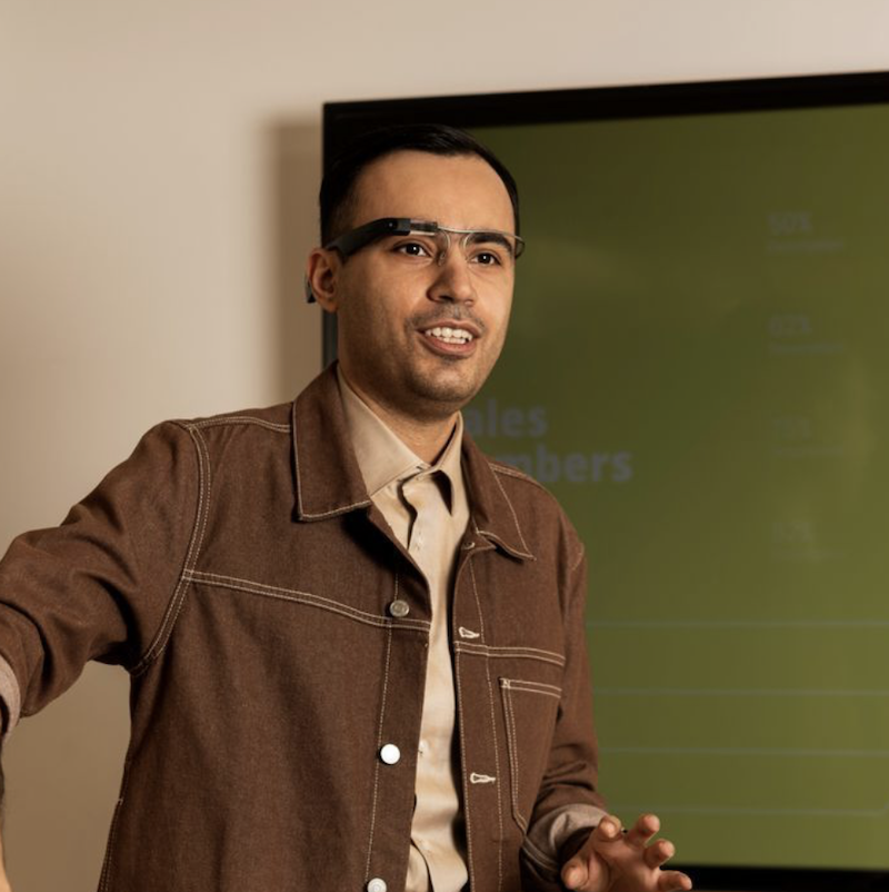 A person in front of a screen wearing the Envision Glasses and giving a presentation