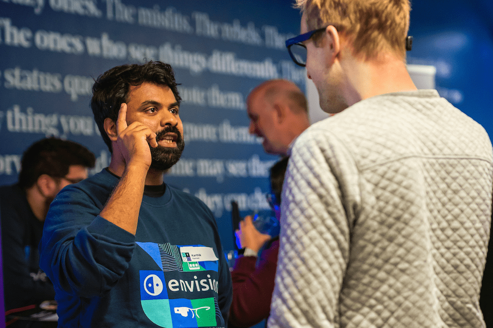 Karthik Khannan showing with the envision glasses to another person how the gestures work