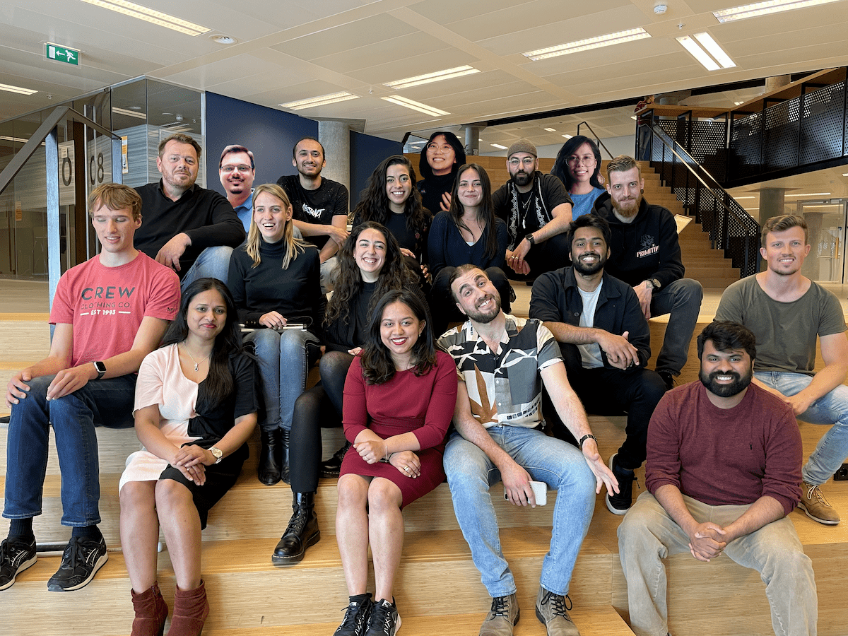 Envision team poses on the office stairs with bright smiles directed at the camera.