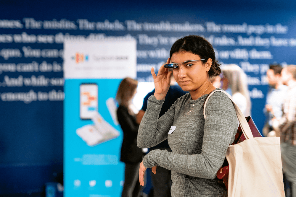 A women looking on camera while using the envision glasses