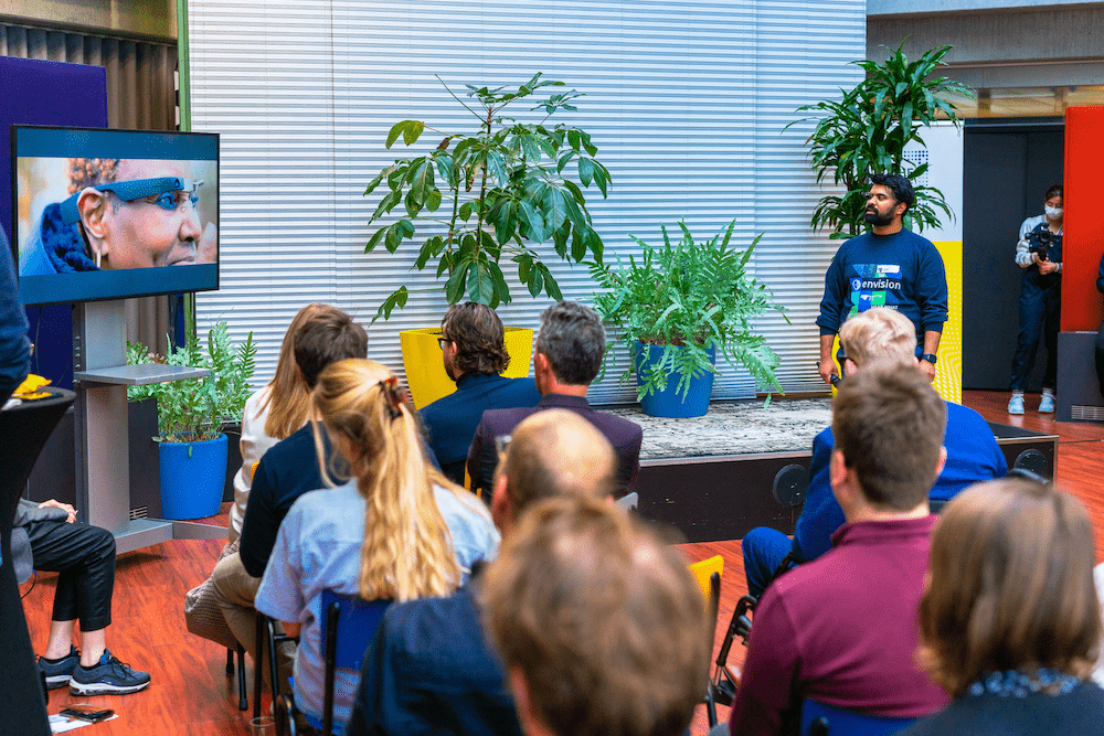 Photo taken at DTFA showing a group of people looking at a video on the tv, on the right is Karthik Kannan the presenter.