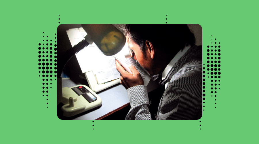 A man uses a manifier to read a document. the blackground is reen with contrasting black dots referencing's Envision's branding.